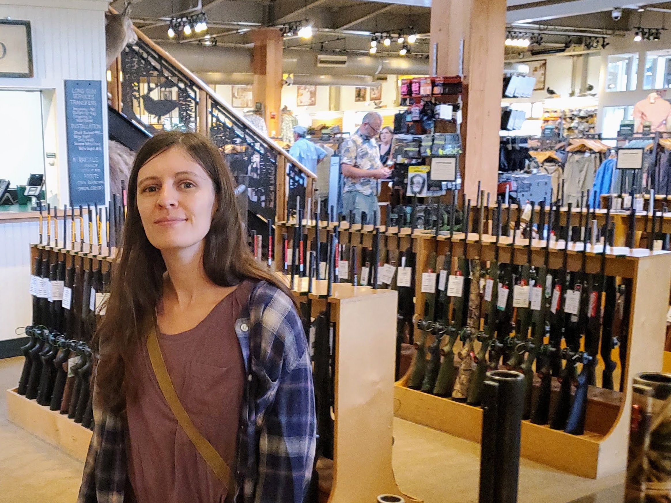 Amber smiling in front of a rack of guns
