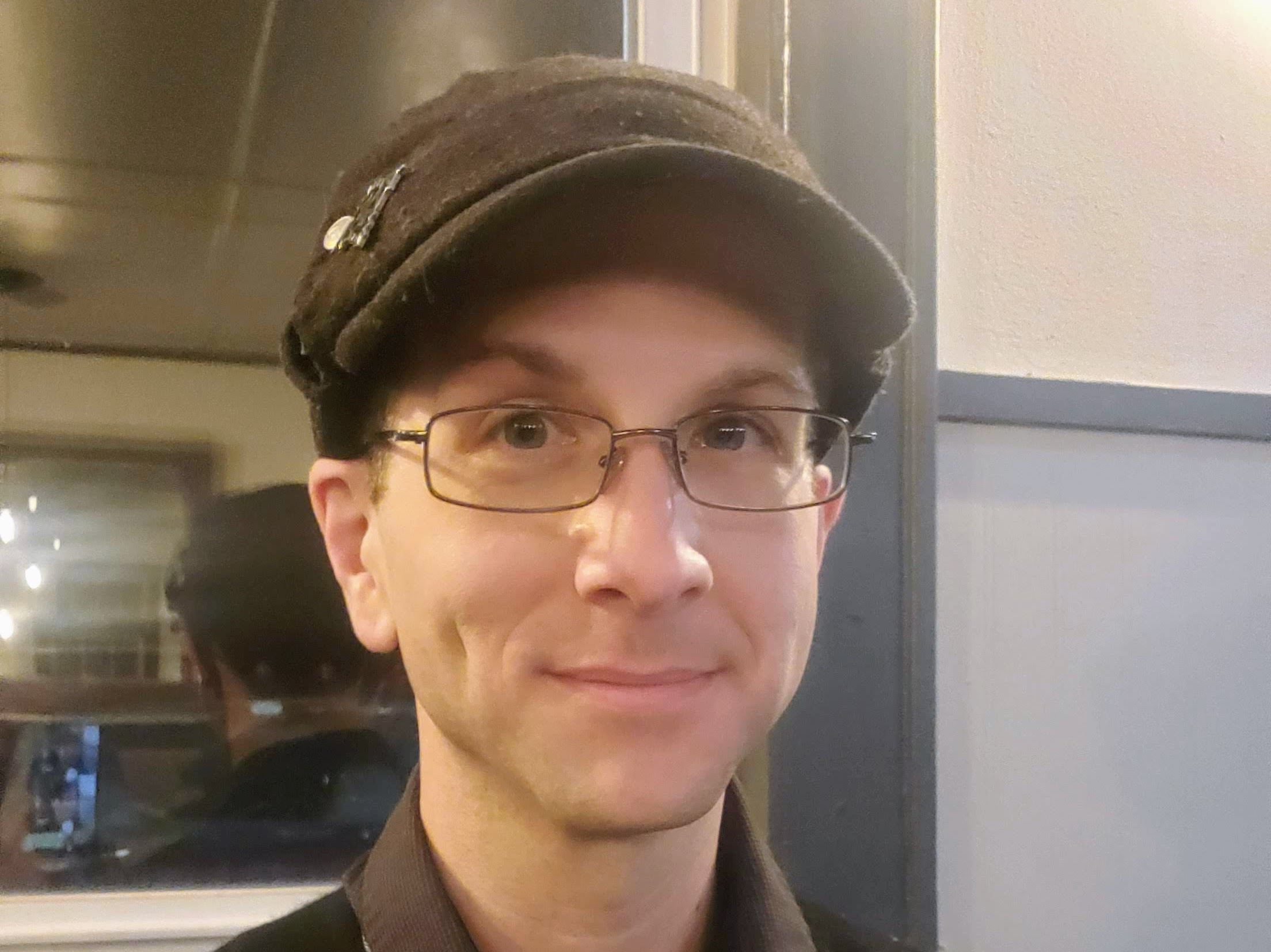 A picture of me slightly smiling at the camera, wearing a hat