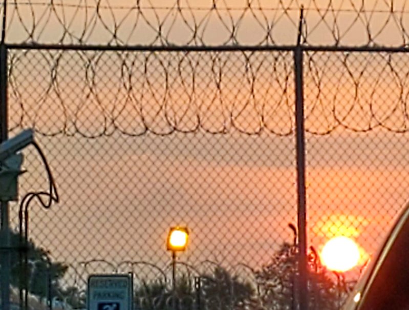 Sunrise through a razor wire fence