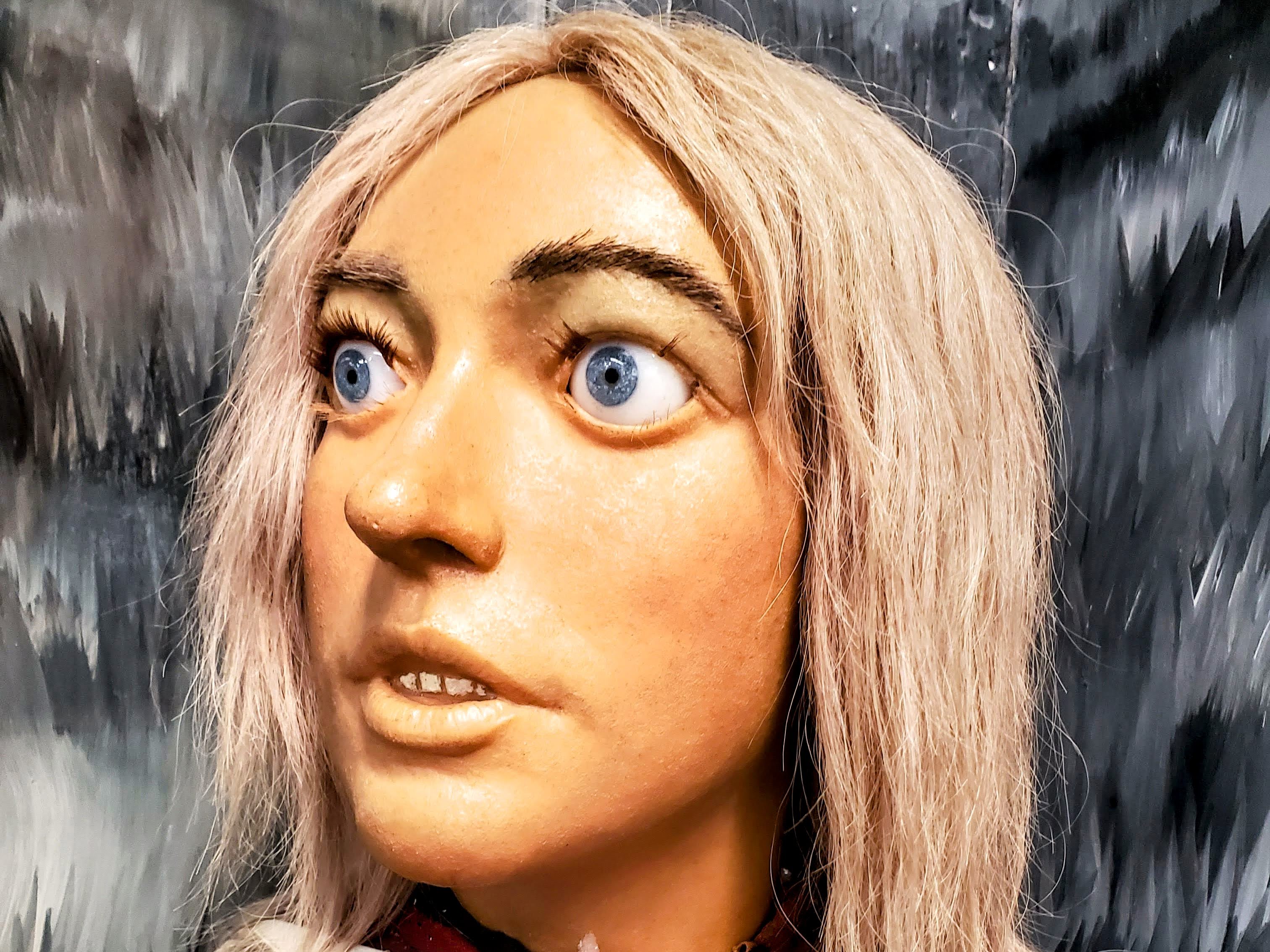 A statue of a blonde witch, its blue eyes wide as if in shock